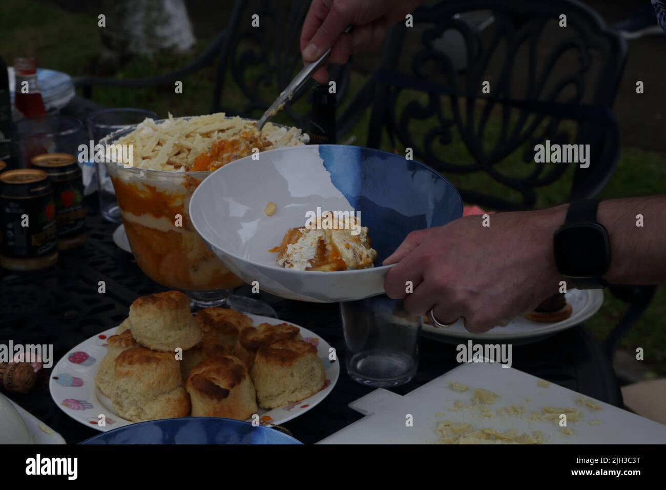 Mann, der die „Platinum Pudding“-Zitrone und Amaretti-Kleinigkeit bei der Street Party serviert, die das Platin-Jubiläum von Queen Elizabeth II in Surrey, England, feiert Stockfoto