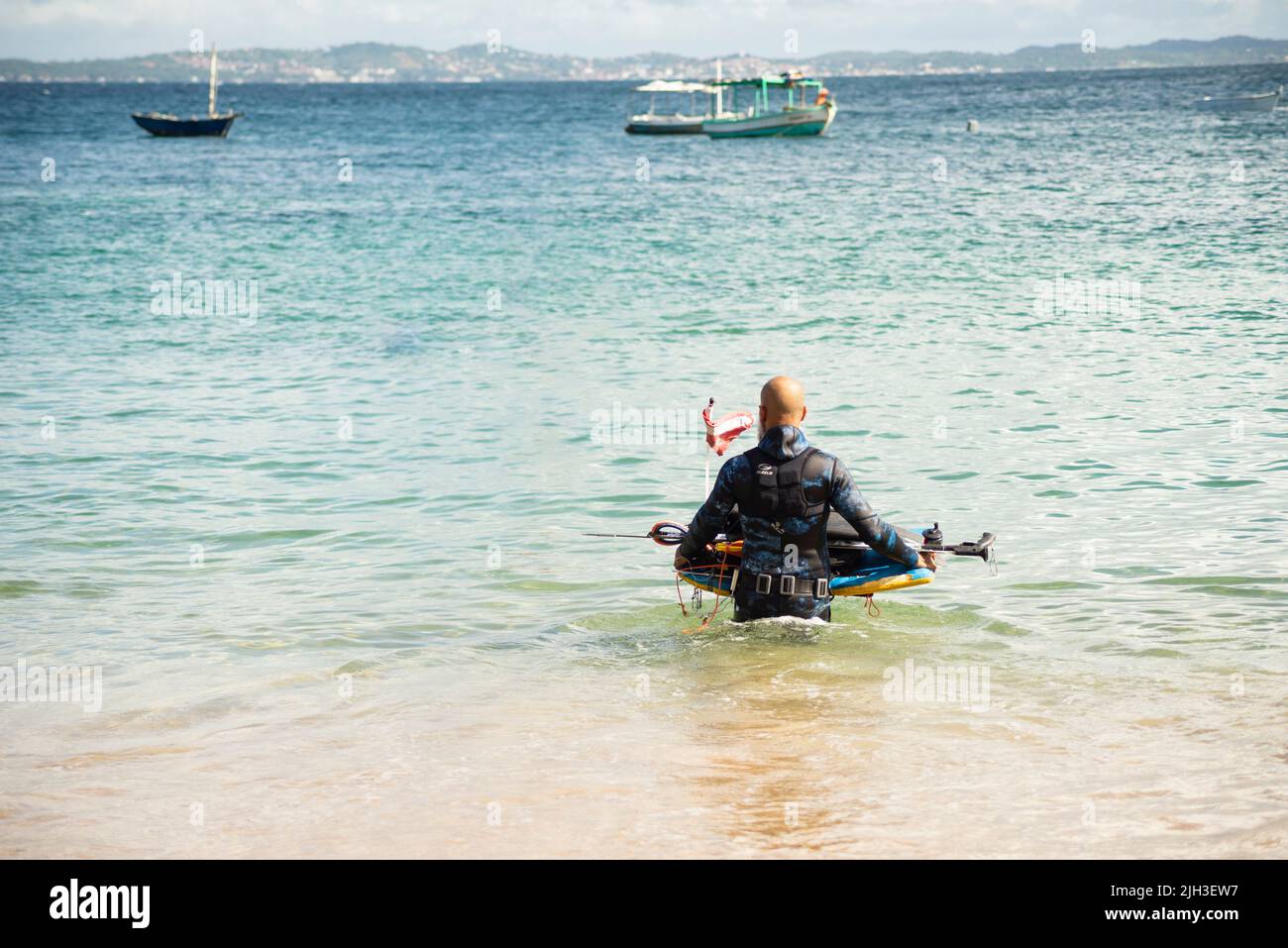 Mann, der mit Tauchausrüstung ins Meer kommt. Strand Porto da Barra, in Salvador, Bundesstaat Bahia, Brasilien. Stockfoto