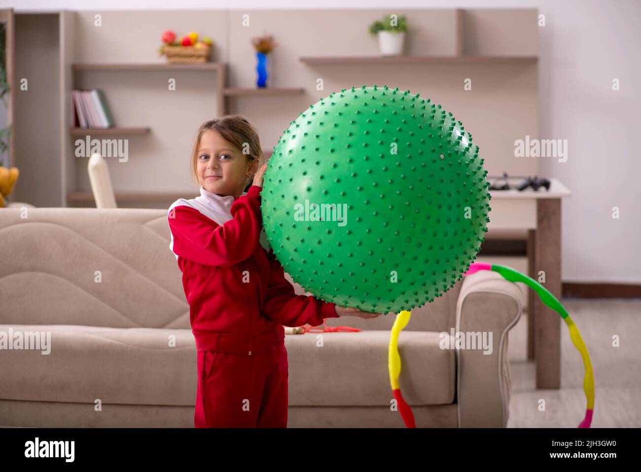 Junges kleines Mädchen, das zu Hause Sportübungen macht Stockfoto