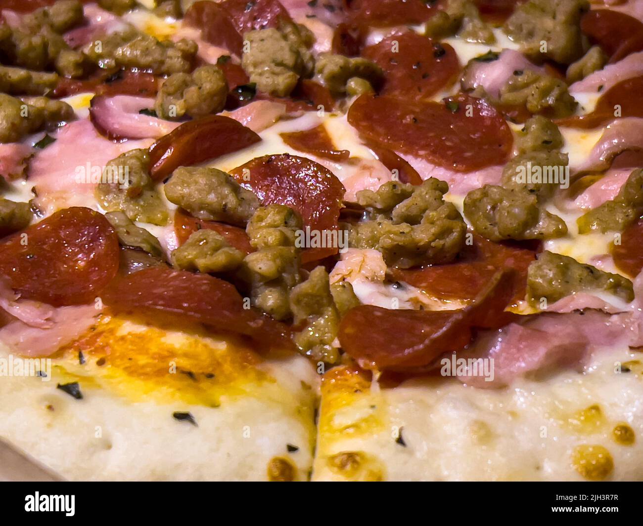 Nahaufnahme, selektiver Fokus auf eine Pizza für Fleischliebhaber in einem Karton Stockfoto