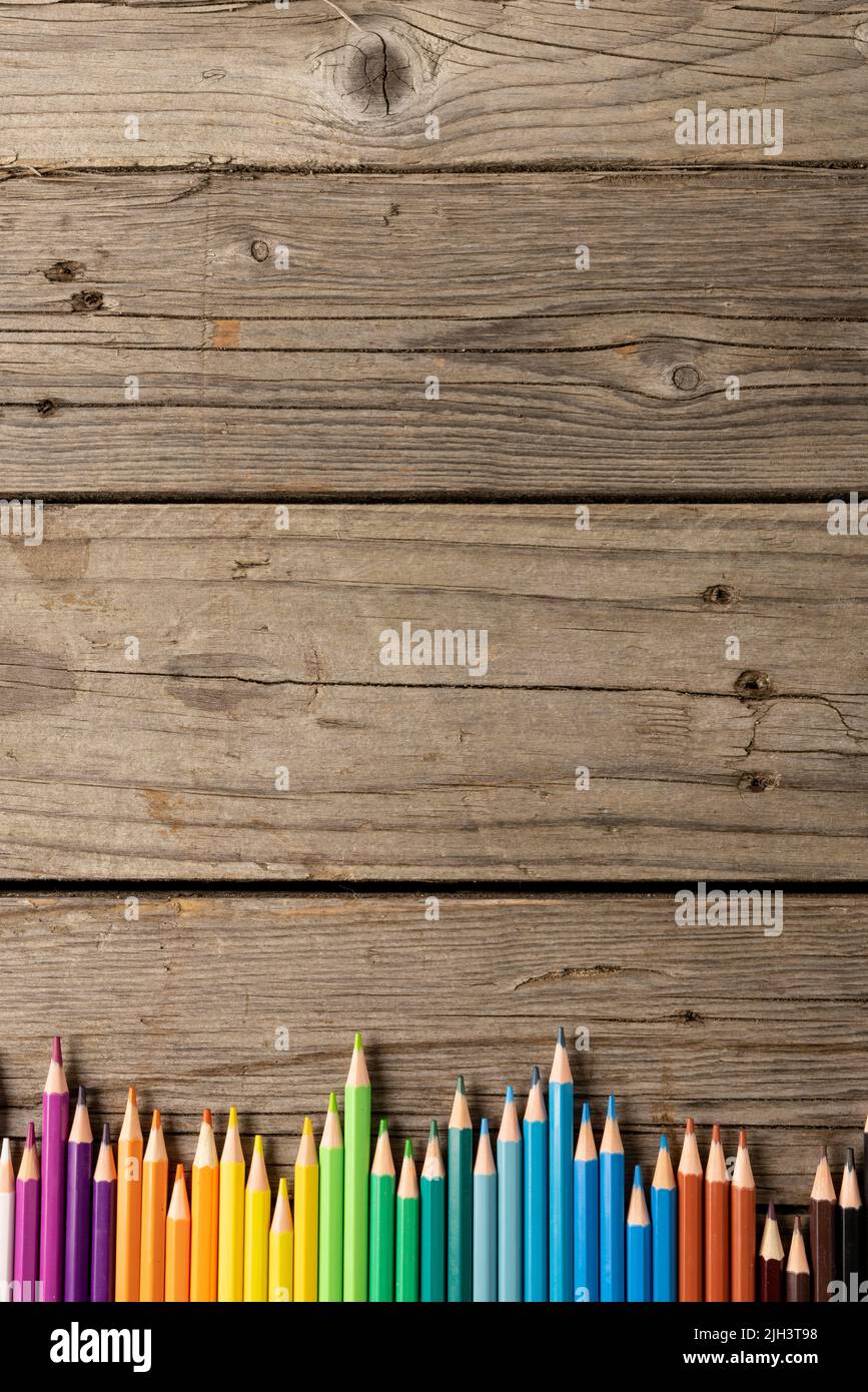 Vertikale Komposition von bunten Buntstiften auf Holzhintergrund Stockfoto