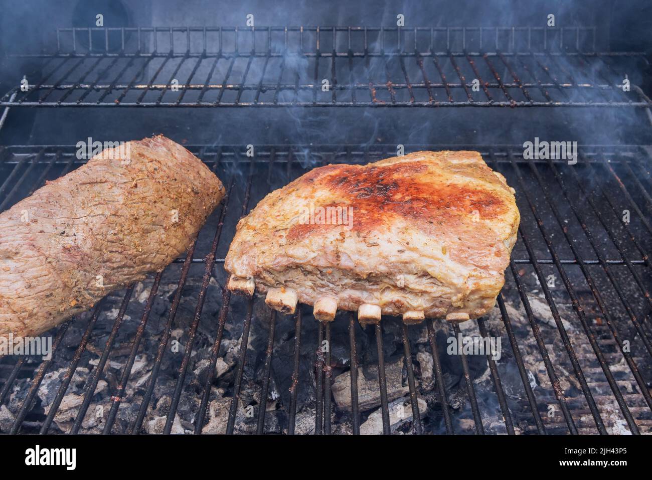 Amerikanische Küche mit gegrilltem Rindersteak und Schweinerippchen auf heißem Grill Stockfoto