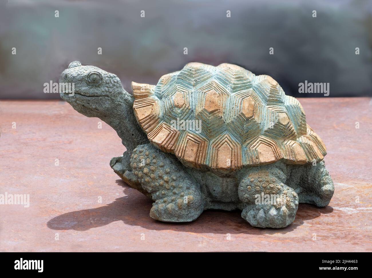 Steinschildkröten-Skulptur sieht aus, als sei er unterwegs, bewacht aber stattdessen den Garten in glücklicher Stille Stockfoto