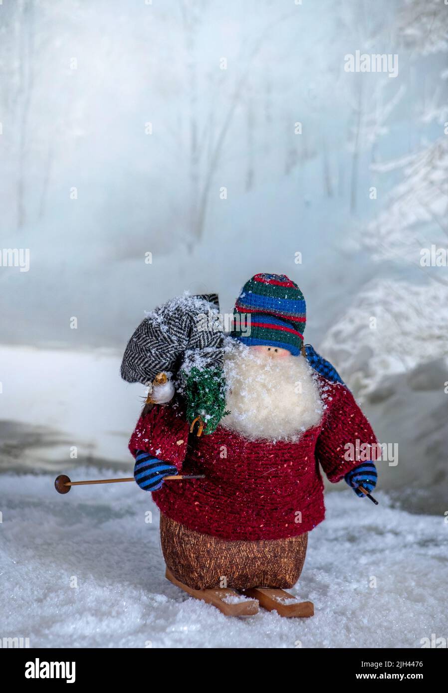 Komische Puppe ist ein alter weihnachtsmann auf Skiern und eine winterliche Kulisse, komplett mit seiner Tasche mit Spielzeug und einem winzigen weihnachtsbaum Stockfoto