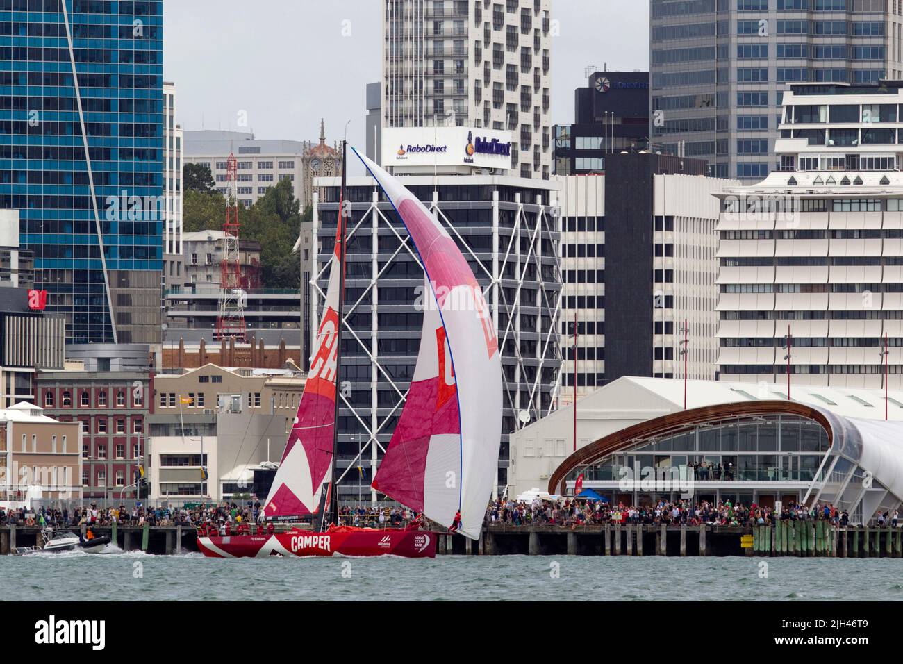 Camper mit Emirates Team Neuseeland passiert große Menschenmassen an den Küsten, während sie beim Rennen im Hafen im Rahmen des Volvo Ocean Race, Auckland, Stockfoto