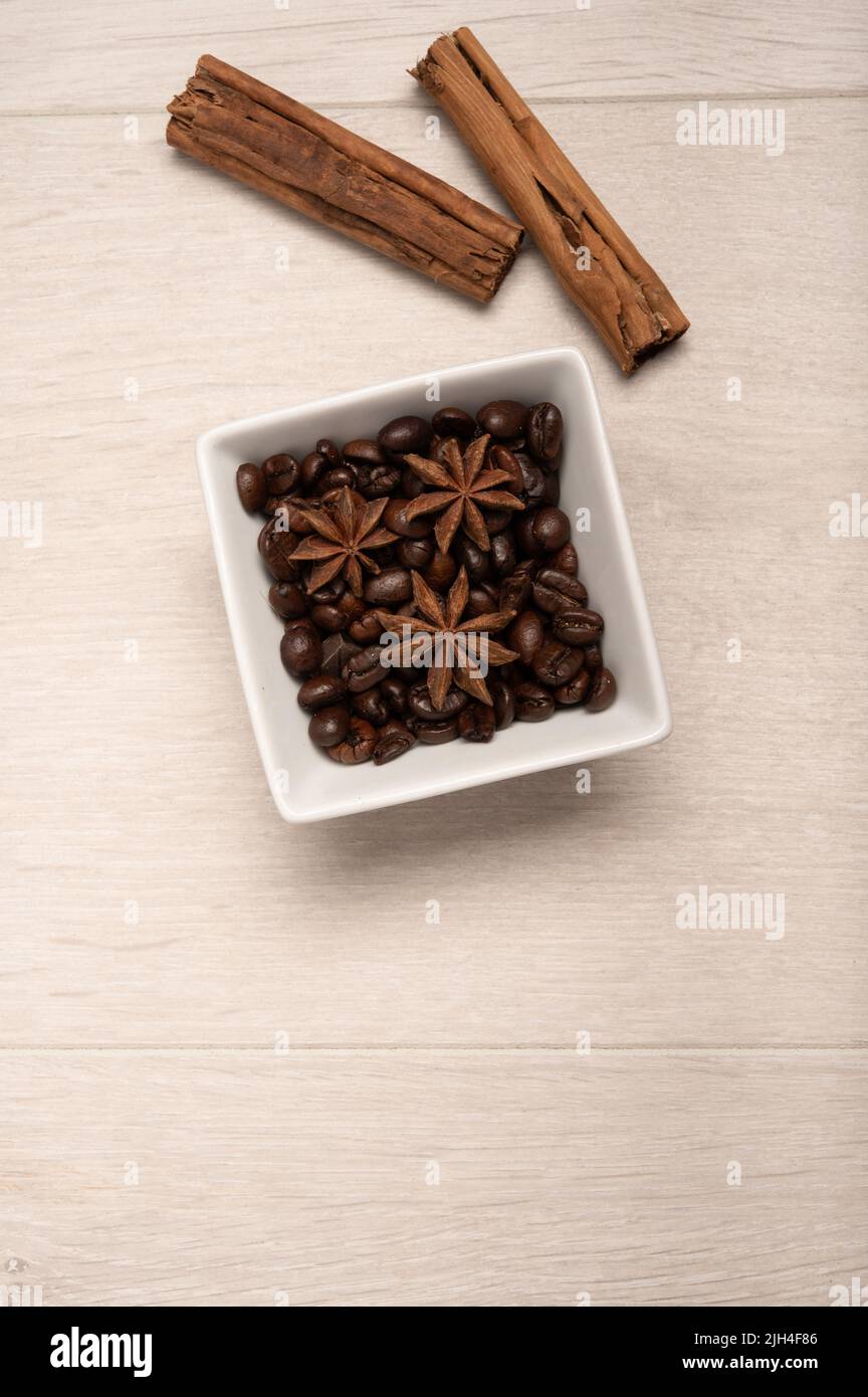Geröstete Kaffeebohnen Zimt und Sternanise auf hellem Holzhintergrund Stockfoto