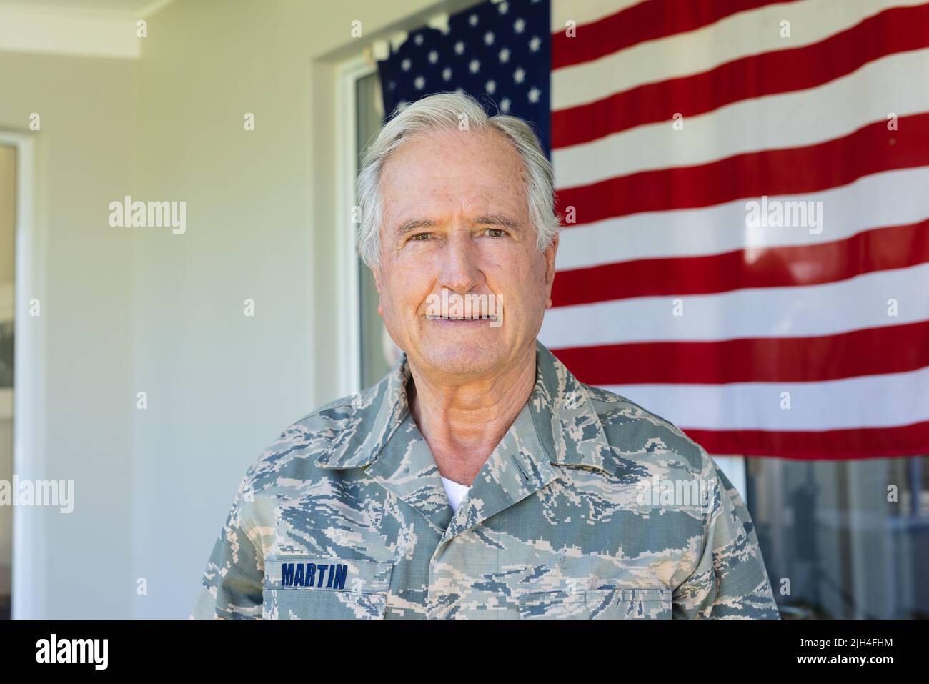 Porträt eines kaukasischen Soldaten in Tarnkleidung, der gegen die Flagge amerikas steht Stockfoto