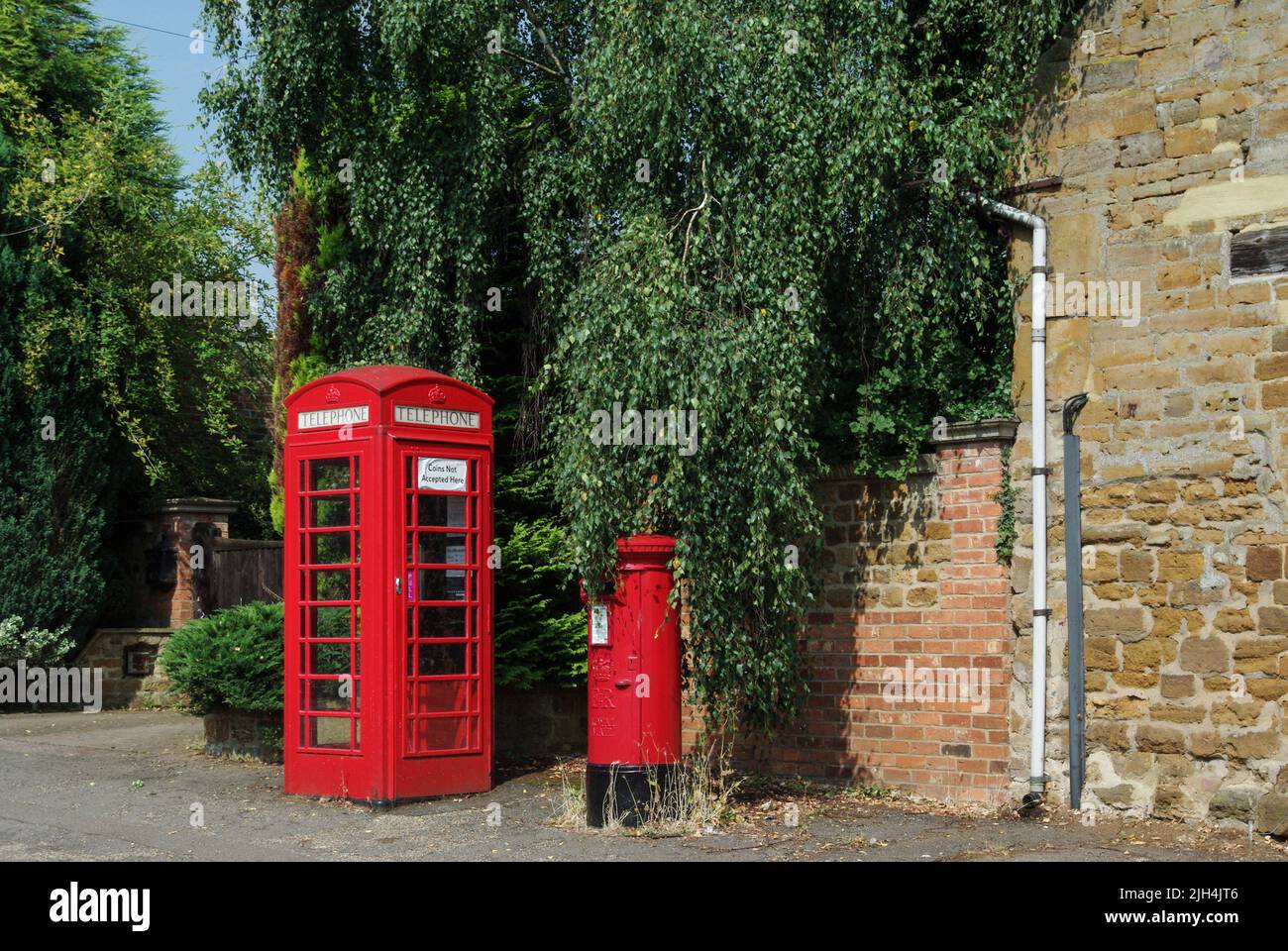 Rote Telefondose und rote Briefkasten nebeneinander im Dorf Spratton, Northamptonshire, Großbritannien Stockfoto