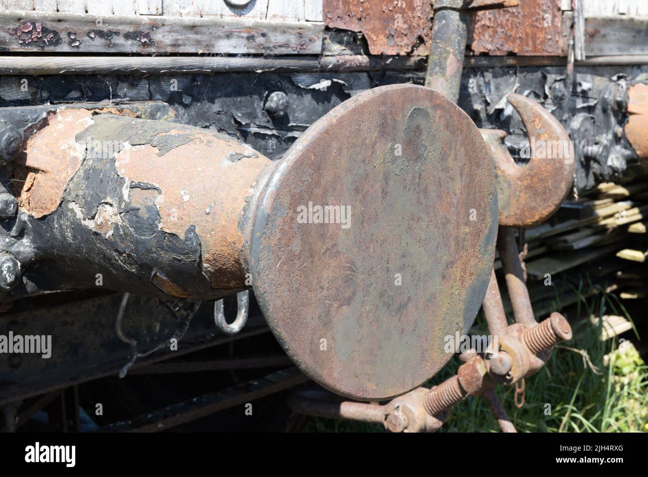 Rostiger, unrestaurierter Puffer auf einem alten hölzernen Zugwagen Stockfoto