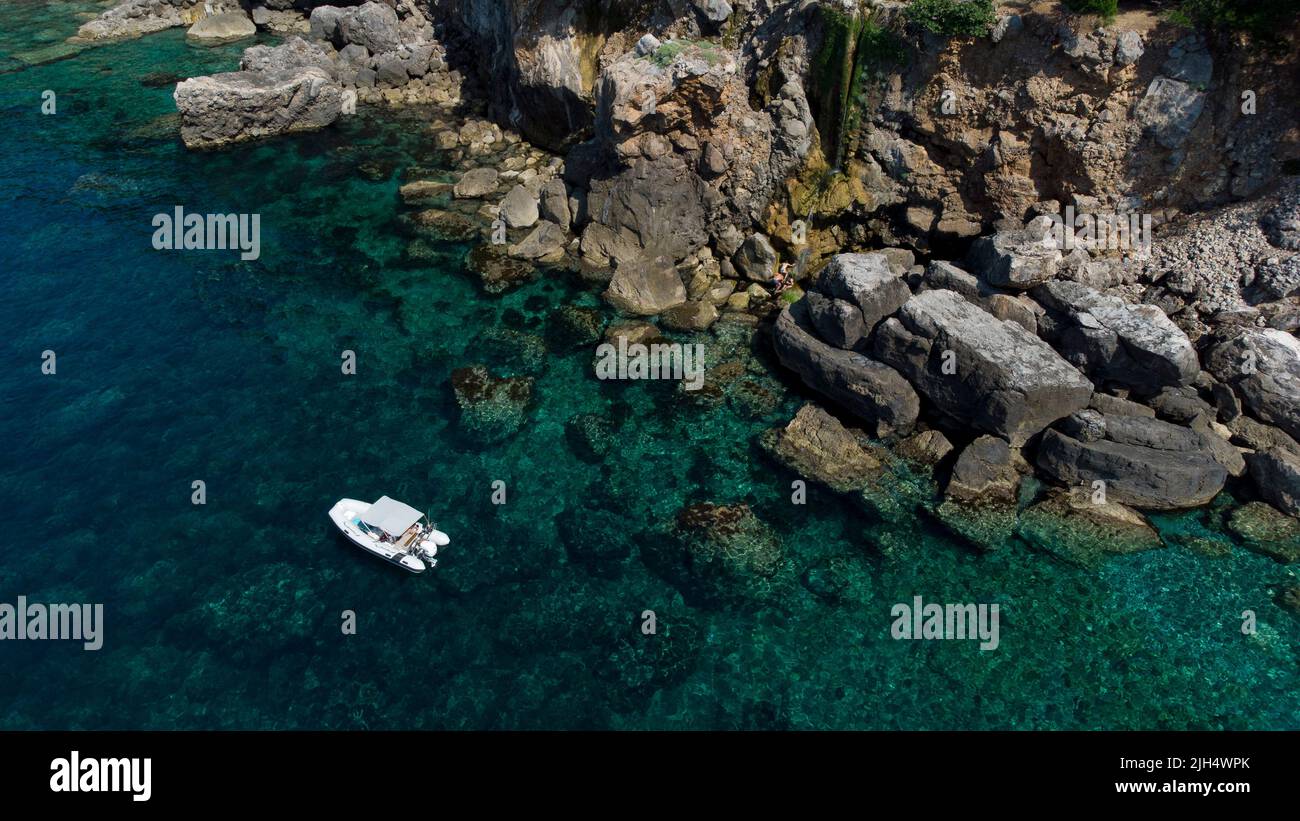 Das Boot liegt in einer wunderschönen Bucht und die Leute genießen es in einer Kaskade. Sa Costera, Mallorca. Stockfoto