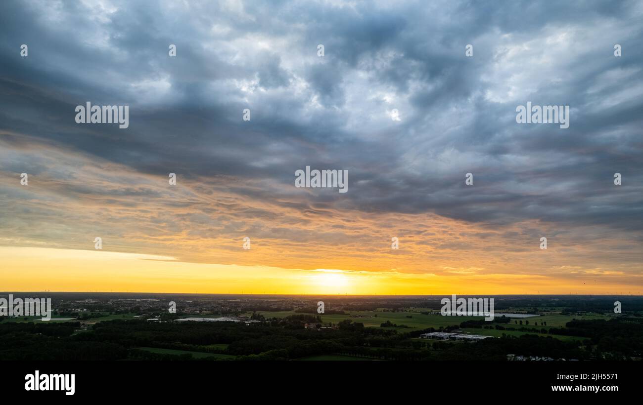 Luftaufnahme erstaunlicher Sonnenuntergang über den Vororten mit der Stadt unter dramatischer Regenwolke. Globaler Erwärmungs-Effekt Schwarzes Gewitter dramatische Regenwolken, dramatischer Himmel, von einer Drohne geschossen. Hochwertige Fotos Stockfoto