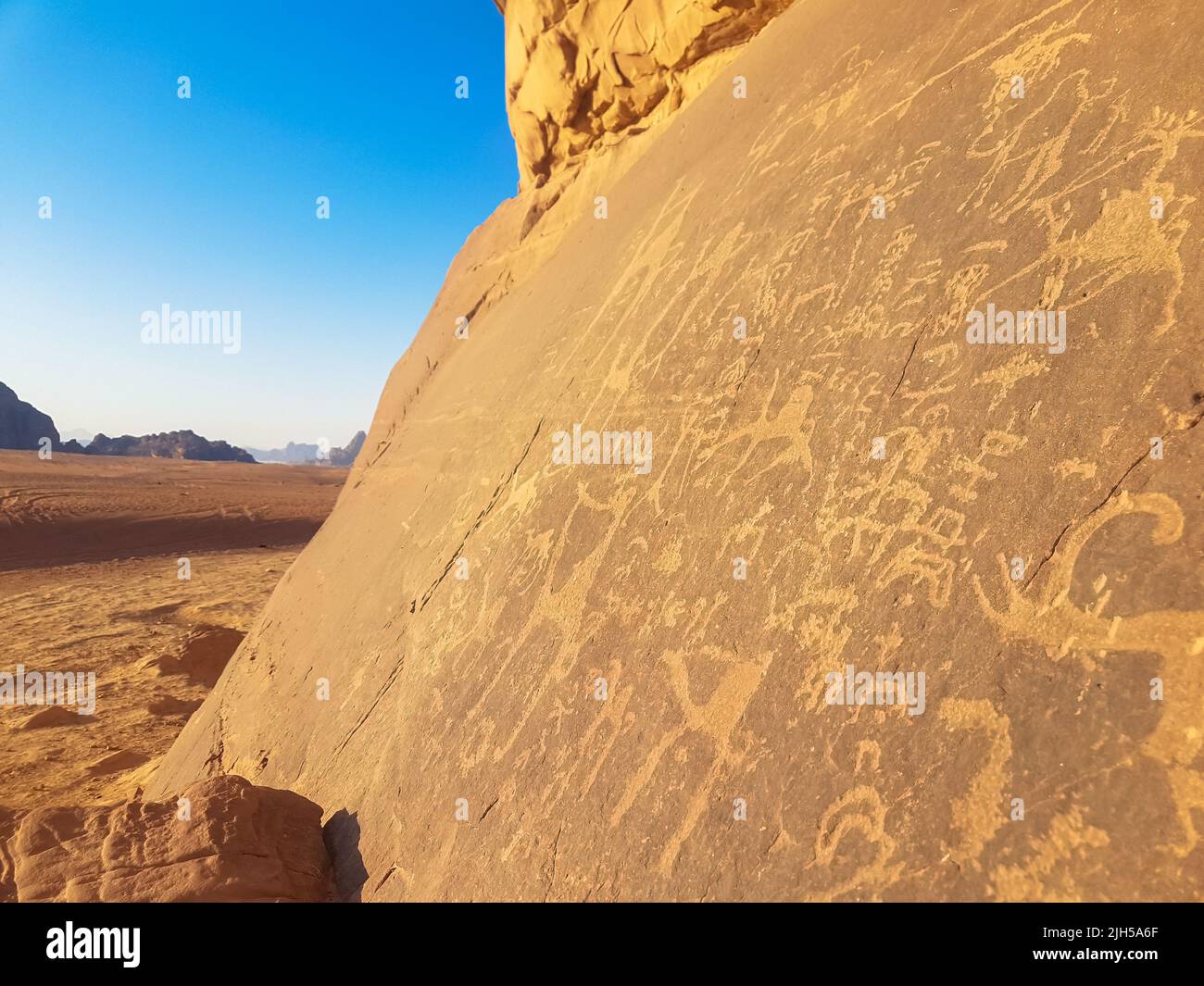 Sandsteinfelsen mit prähistorischer Kunst. Prähistorische Zivilisation hinterließ ihre primitiven Zeichnungen auf einer Kalksteinklippe in der Wadi Rum Wüste, Jordanien. Stockfoto