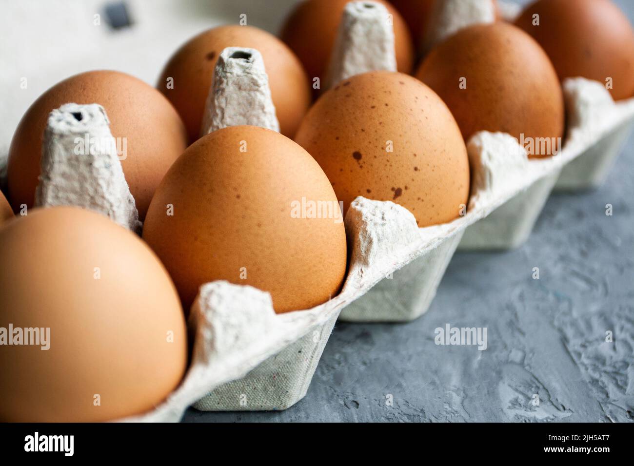 Gepunktete braune Eier liegen in einem Papierbeutel auf einem grauen Betontisch Stockfoto