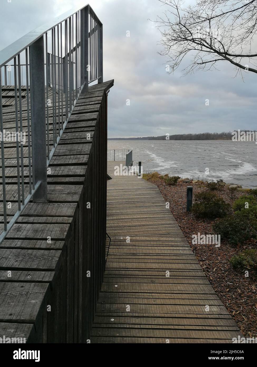 Ein hölzerner Pier führt zu einer Aussichtsplattform. Holzplatz vor dem Fluss. Holzbrett mit einem Zaun. Pier mit Balkon. Stockfoto