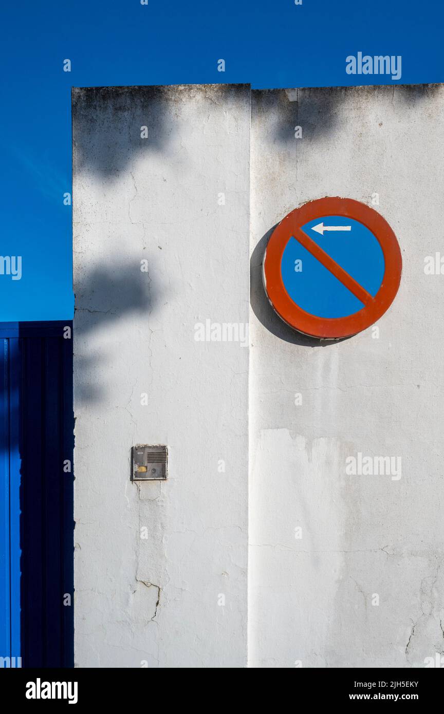 Ein rot-blaues No Parking Schild an einer weißen Wand in Spanien mit leuchtendem Blau und Rot Stockfoto