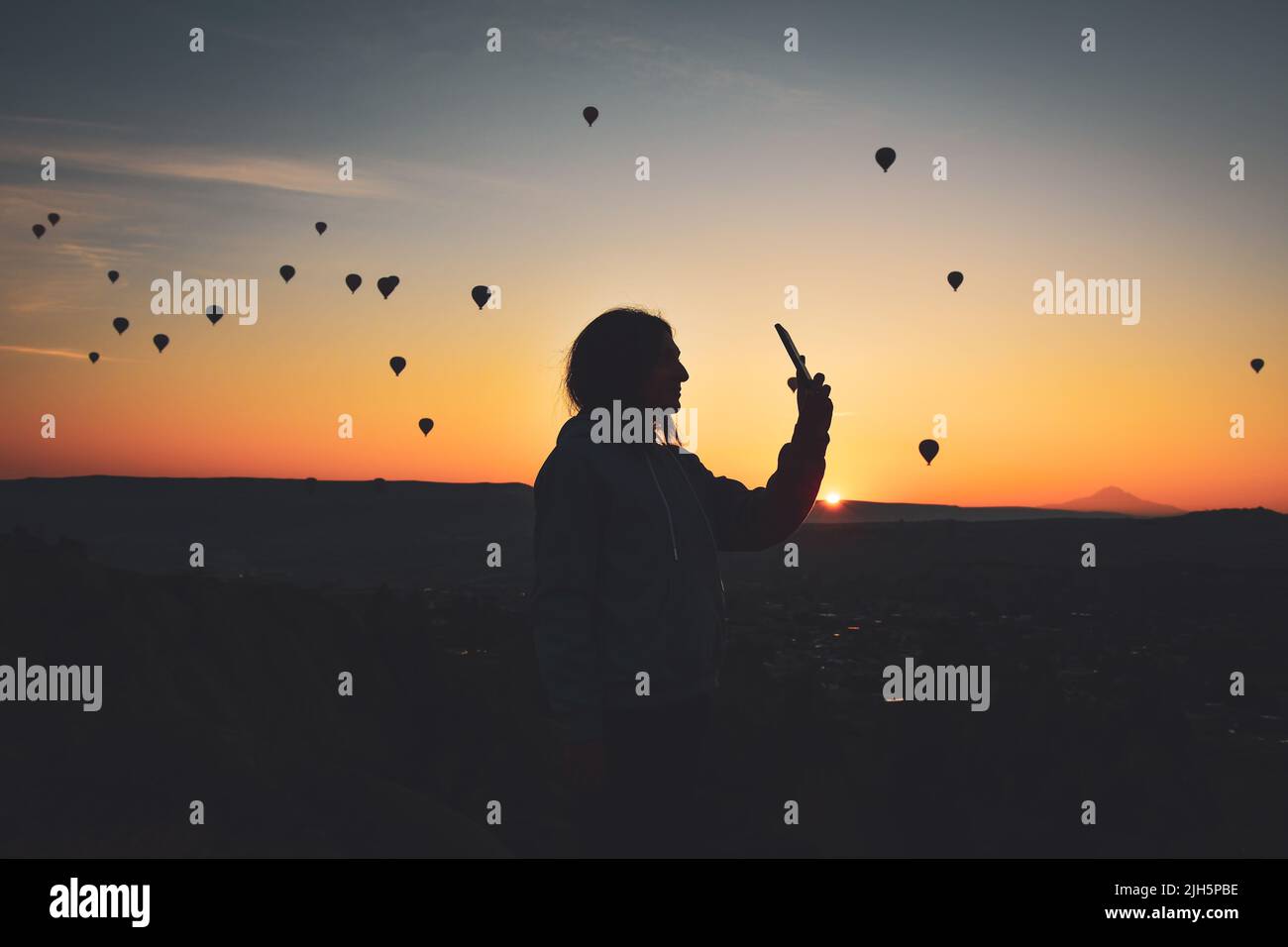 Silhouette des Smartphones in den Händen der Frau, die Bilder von einer schönen Landschaft und Luftballons in Kappadokien. Sunrise Time, verträumtes Reisekonzept Stockfoto