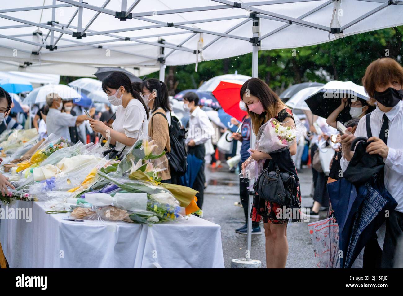 Tokio, Japan . 15.. Juli 2022. 15. Juli 2022. Seit dem Tod des ehemaligen Premierministers Shinzo Abe ist eine Woche vergangen. Im Hauptquartier der LDP in Tokio wurden auf dem Parkplatz ein Tisch mit Bucheinstieg und ein Blumenanbietstand aufgestellt, und Menschen kamen, um nacheinander um den ehemaligen Premierminister zu trauern. Während des gelegentlichen heftigen Regens am Freitag boten viele Menschen Blumen und Gebet an. Die Linie zum Tisch erstreckte sich mehrere hundert Meter vom Parteihauptsitz bis zur Nationaldiätebibliothek, und Menschen jeden Alters standen an der Reihe. (Foto: Mihoko Owada/Sipa USA) Quelle: SIPA USA/Alamy Live News Cr Stockfoto