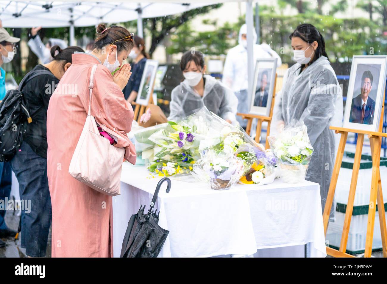 Tokio, Japan . 15.. Juli 2022. 15. Juli 2022. Seit dem Tod des ehemaligen Premierministers Shinzo Abe ist eine Woche vergangen. Im Hauptquartier der LDP in Tokio wurden auf dem Parkplatz ein Tisch mit Bucheinstieg und ein Blumenanbietstand aufgestellt, und Menschen kamen, um nacheinander um den ehemaligen Premierminister zu trauern. Während des gelegentlichen heftigen Regens am Freitag boten viele Menschen Blumen und Gebet an. Die Linie zum Tisch erstreckte sich mehrere hundert Meter vom Parteihauptsitz bis zur Nationaldiätebibliothek, und Menschen jeden Alters standen an der Reihe. (Foto: Mihoko Owada/Sipa USA) Quelle: SIPA USA/Alamy Live News Cr Stockfoto