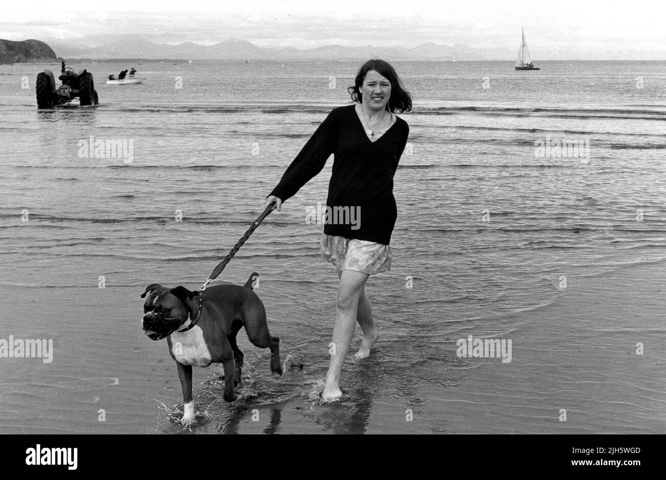 Teenager-Mädchen, die 1967 Boxerhund am Strand von Abersoch in Wales spazierengehen Stockfoto