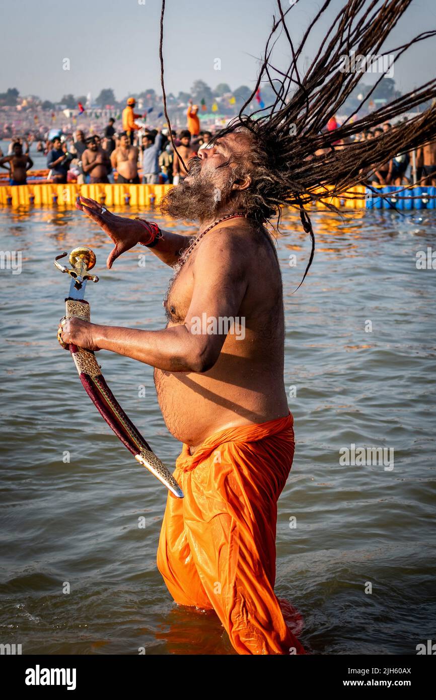 Ein Hindu mit langen Dreadlocks und einem Schwert badet beim Triveni Sangam Kumbh Mela Festival in Allahabad (Prayagraj), Indien. Stockfoto