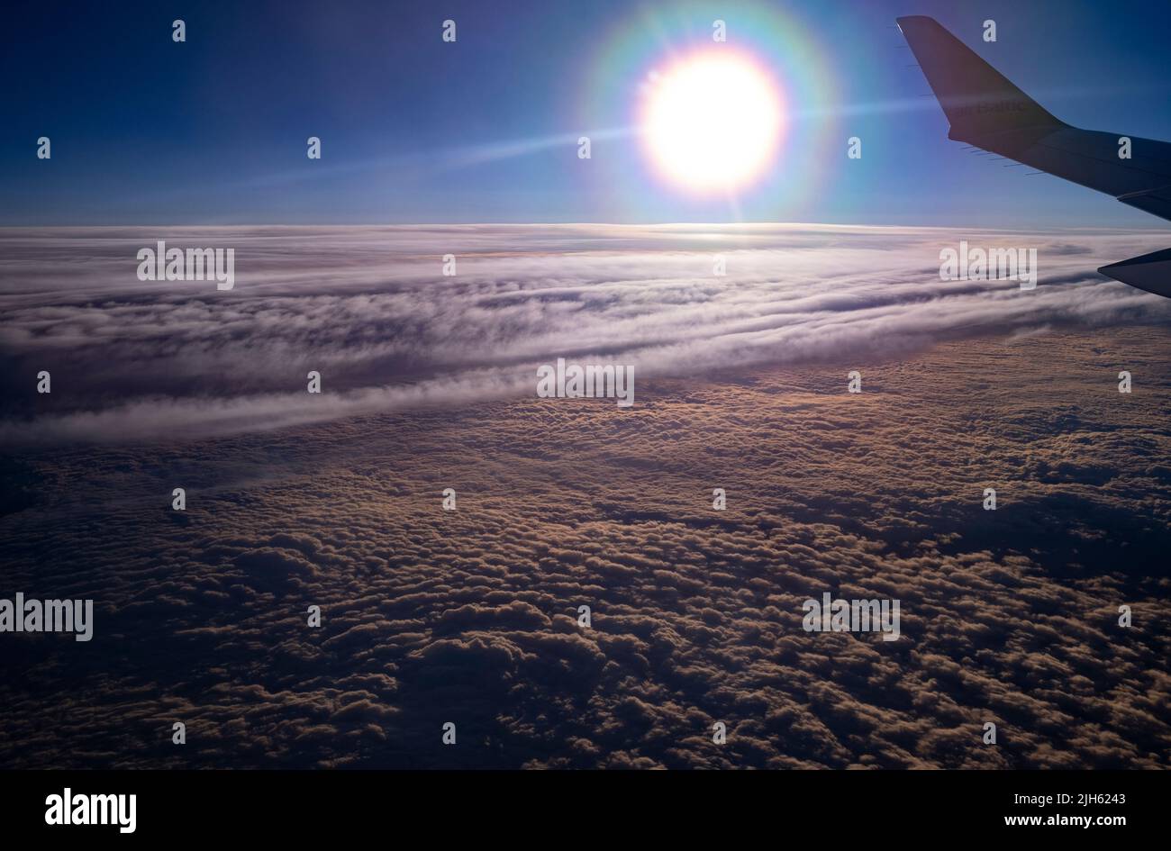 Airbus A220-300 Flügel in Sonnenuntergangslichtern fliegen über Wolken irgendwo über der Ostseeregion in Europa Stockfoto