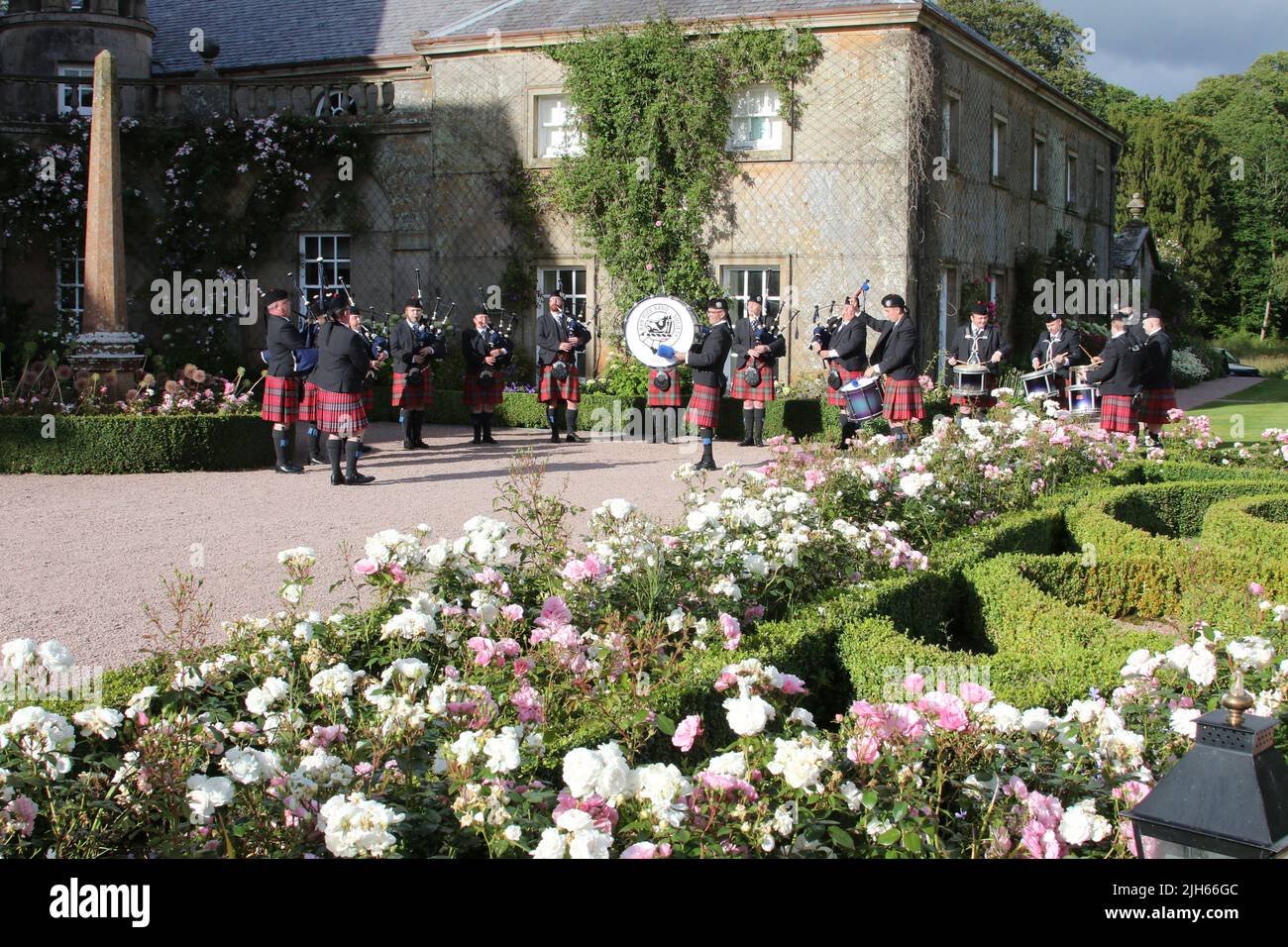 Dumfries House, Cumnock, Schottland, Großbritannien, Ayr Pipe Band spielen vor dem Haus. Tragen Sie traditionelle Outfits Kilts und glengarry Kopfbedeckung. Der Brunnen, der als Mahfouz-Brunnen bekannt ist. Eine Pest in der Nähe sagt: „Ermöglicht durch die Großzügigkeit von HE Mahfouz Marei Murbank bin Mahfouz. Der Brunnen wurde formell von S.R.H Prinz Charles, Herzog von Rothesay, geöffnet 21. Oktober 2014. Der Brunnen ist von einem formellen Garten umgeben Stockfoto