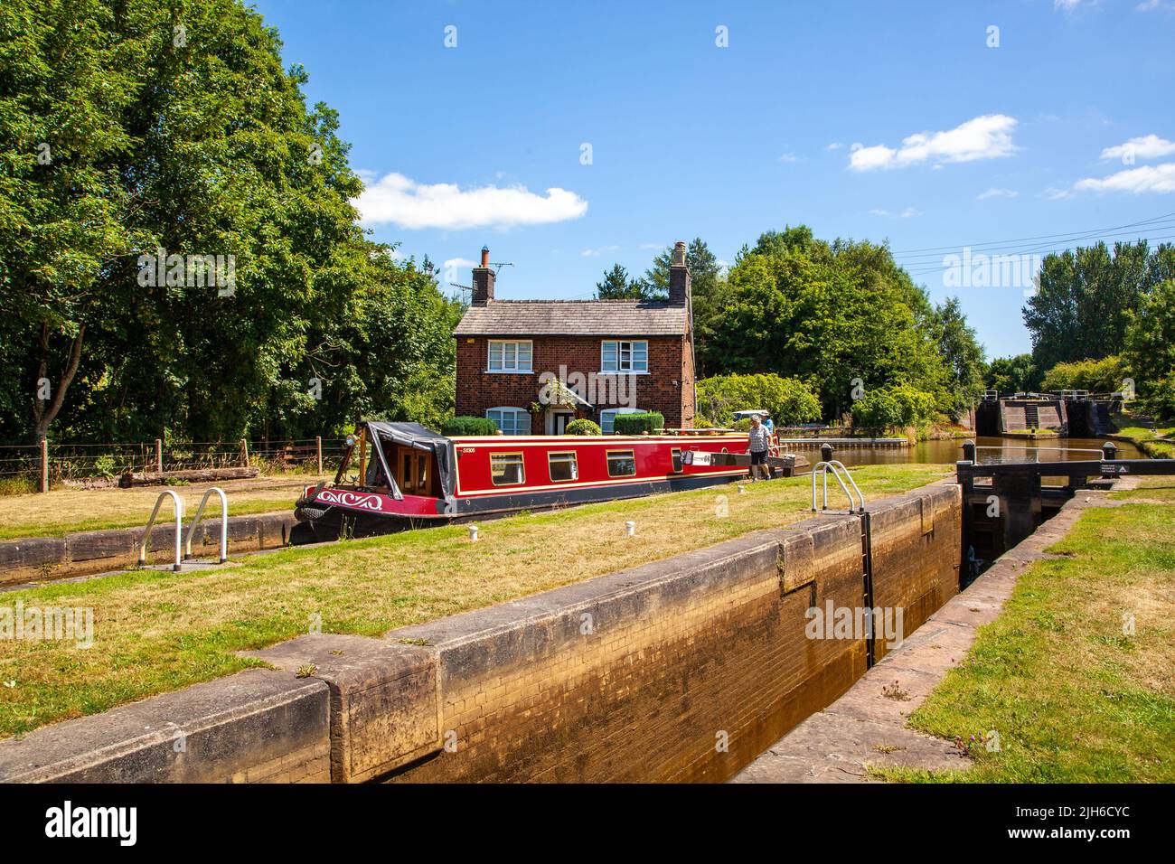 Canal Narrowboat fährt durch Schleusen auf dem Trent und Mersey Kanal, während es durch das Dorf Wheelock Cheshire England fährt Stockfoto