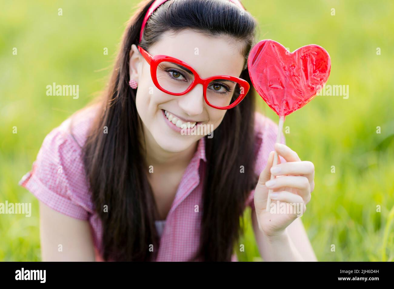 Frau mit Brille und Herz Lolly Stockfoto