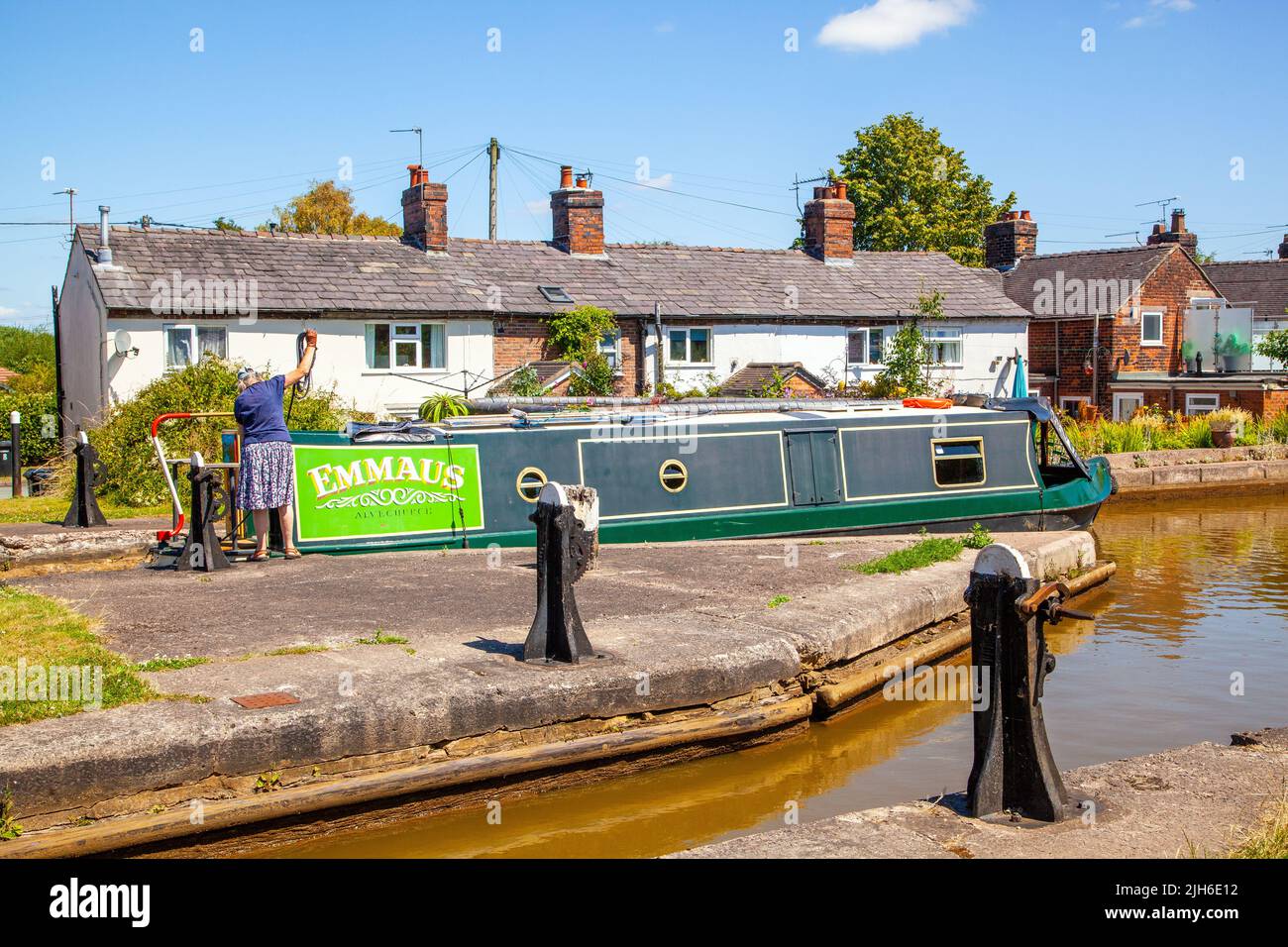 Frau auf einem Kanalurlaub mit einem Schmalboot, das eine Durchgangsschleuse 63 Malkins Bank Bottom Lock passiert, auf dem Trent und Mersey Kanal bei Malkins Bank Cheshire Stockfoto