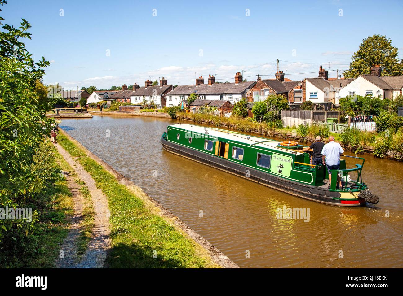 Menschen auf einem Kanal-Schmalboot-Urlaub vorbei Kanal Seite Hütten nähern sich Schleuse 63 bei Malkins Bank Cheshire auf dem Trent und Mersey Kanal Stockfoto