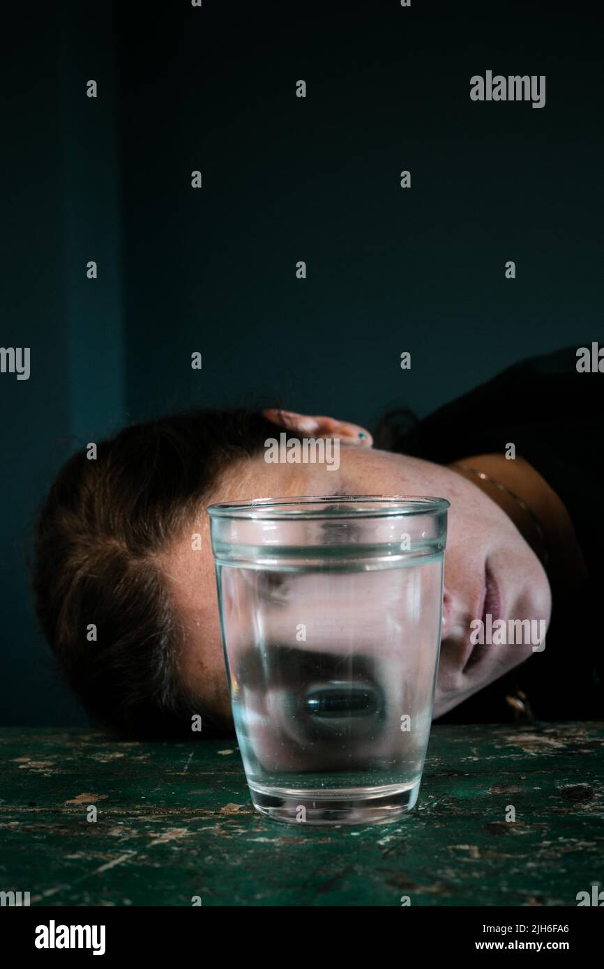 Das gruselige Gesicht einer Frau spiegelte sich in einem Glas Wasser wider Stockfoto