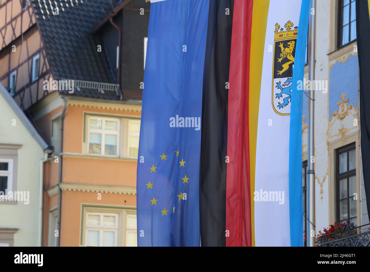 Die bayerische Flagge, die vor einem Rathaus neben der EU- und der deutschen Flagge hängt. Coburg, Deutschland Stockfoto