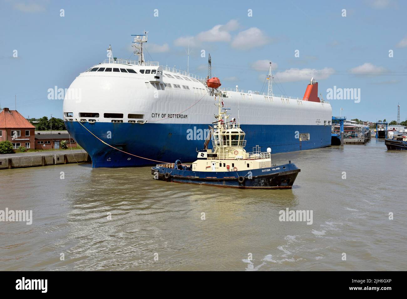 Schlepper bewegen ein Spezialschiff, das mit Autos beladen ist, im Außenhafen Emden, Ostfriesland, Niedersachsen, Deutschland Stockfoto