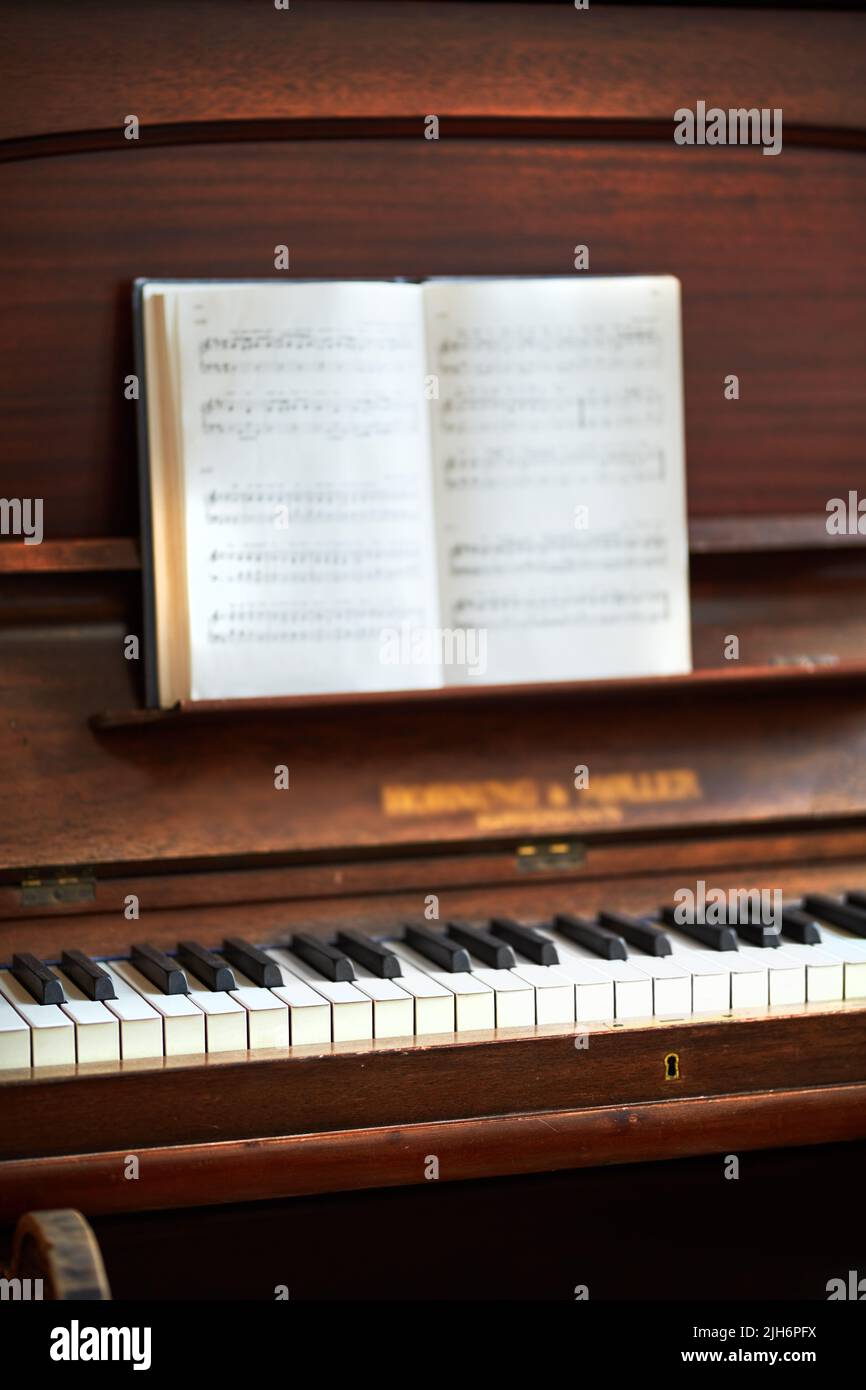 Altes Vintage-Klavier mit musikalischen Noten bei einem Festival klassischer Musik. Eine antike Holztastatur mit einem Kompositionsbuch, das bereit ist für eine Melodie zu sein Stockfoto