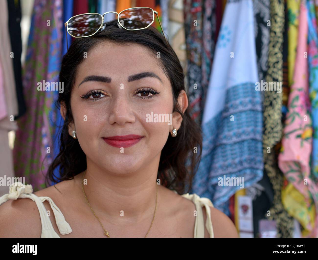 Attraktive, schöne junge hispanische Latina mexikanische Brünette Frau mit Augen-Make-up, rotem Lippenstift und modernen Augenbrauen trägt ihre Sonnenbrille auf der Stirn. Stockfoto