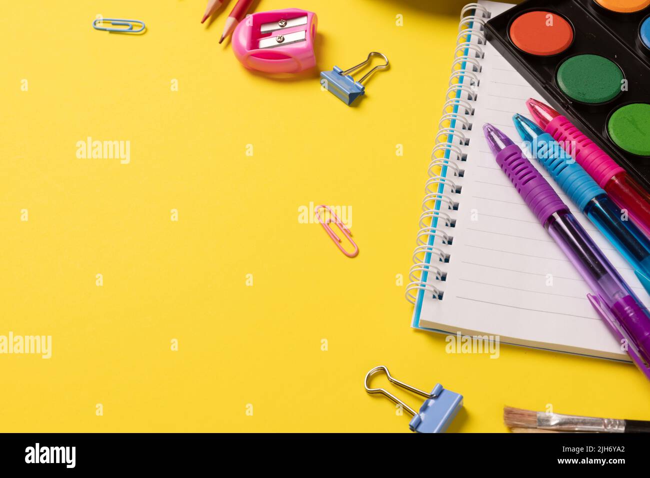 Stellen Sie sich verschiedene Büromaterialien und Plastikutensilien, Farben, Buntstifte auf gelbem Hintergrund vor Stockfoto