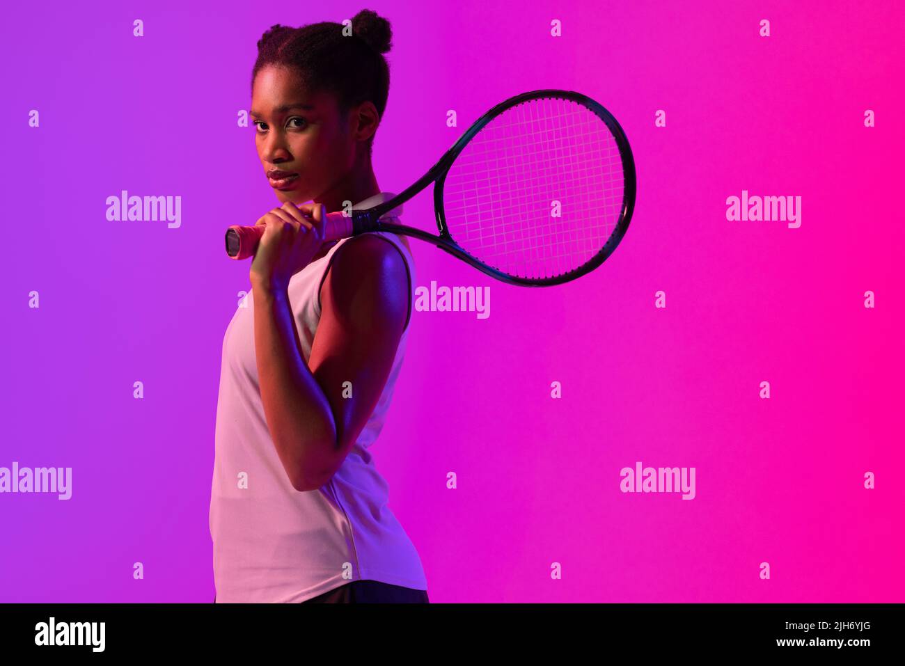 Bild einer afroamerikanischen Tennisspielerin in violettem und pinkem Neonlicht Stockfoto