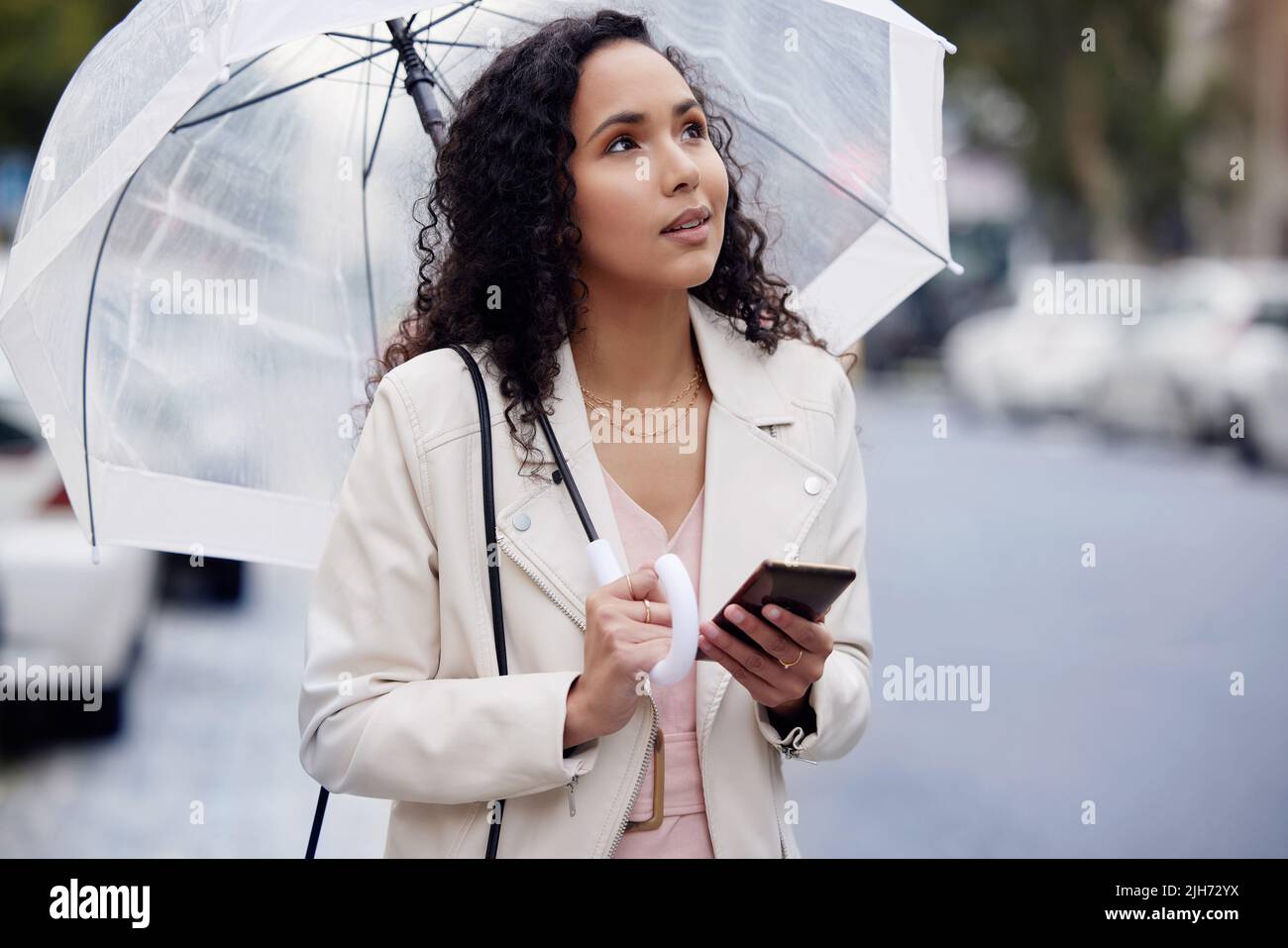 Lassen Sie sich nicht in ungewohnten Straßen verfangen. Eine junge Frau, die verloren aussieht, während sie einen Regenschirm hält und in der Stadt läuft. Stockfoto