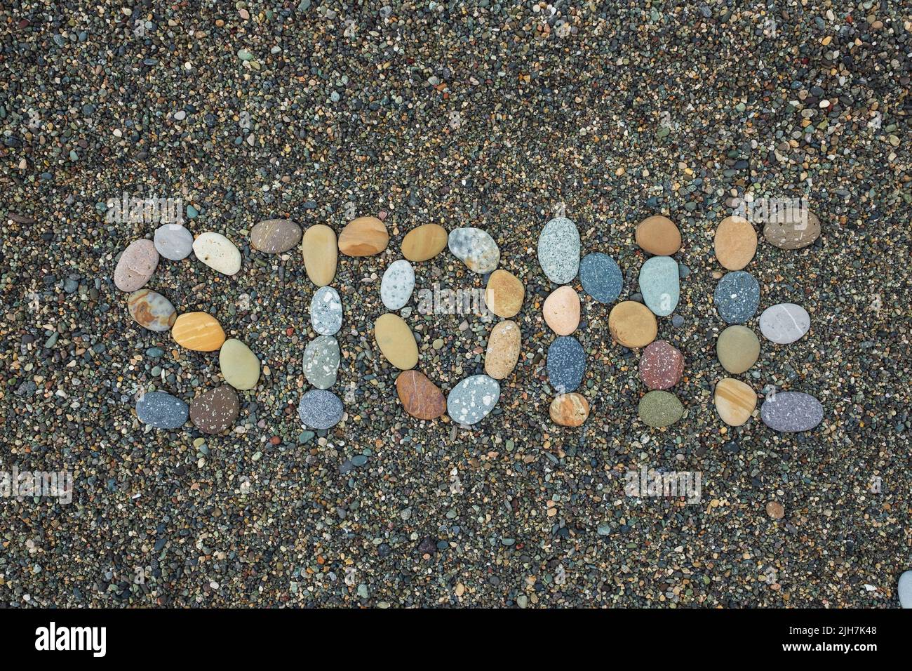 Textstein aus Steinen am Sandstrand. Stockfoto