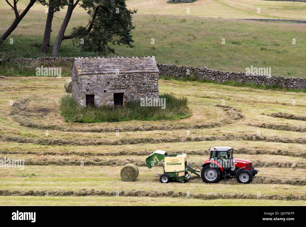 Sommerhaymaking, Hawes, Wensleydale, Yorkshire Dales National Park. Ein Traktor und eine Ballenpresse verwandeln gemähtes Gras in runde Ballen, die als Winterfutter verwendet werden können. Stockfoto