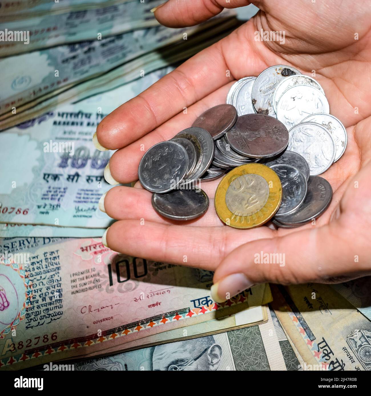 Seltene alte indische Bankrupien-Münzen fallen auf Geldscheine, fallen nach unten indische Rupien-Münzen auf hundert Rupien-Banknoten, indische Währungsmünzen fallen Stockfoto
