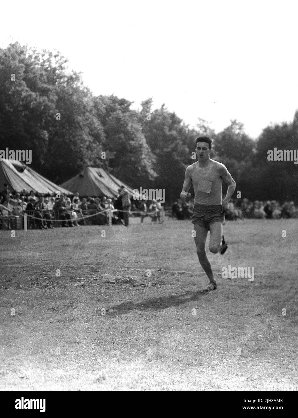 1960s, historisch, ein männlicher Athlet, der draußen auf einem Grasfeld läuft, England, Großbritannien. Stockfoto