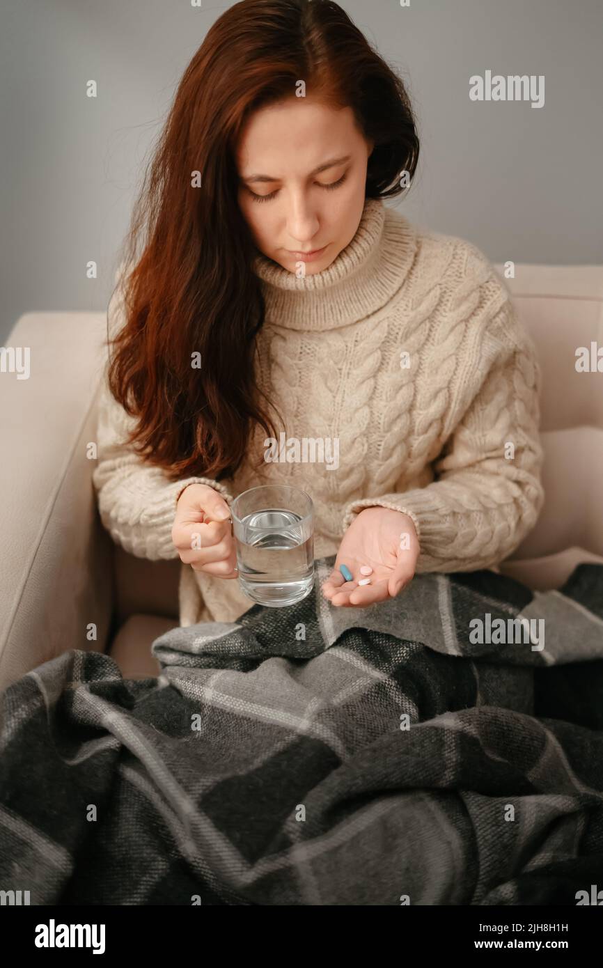 Junge Frau zu Hause behandelt Krankheit mit Pillen. Stockfoto