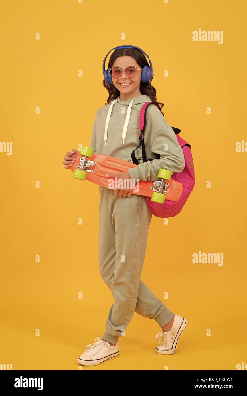 Glückliches Kind in activewear hält Penny Board gelben Hintergrund, Skateboarding Stockfoto