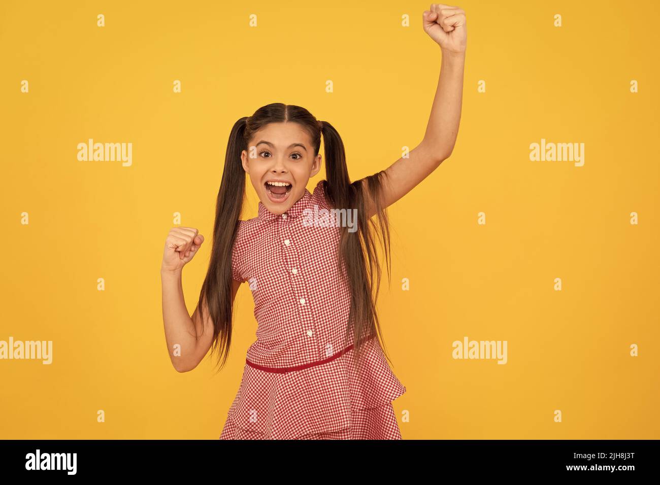 Glücklich enthusiastischen Kind machen gewinnende Hand Geste schreiend und feiert gelben Hintergrund, Freude Stockfoto