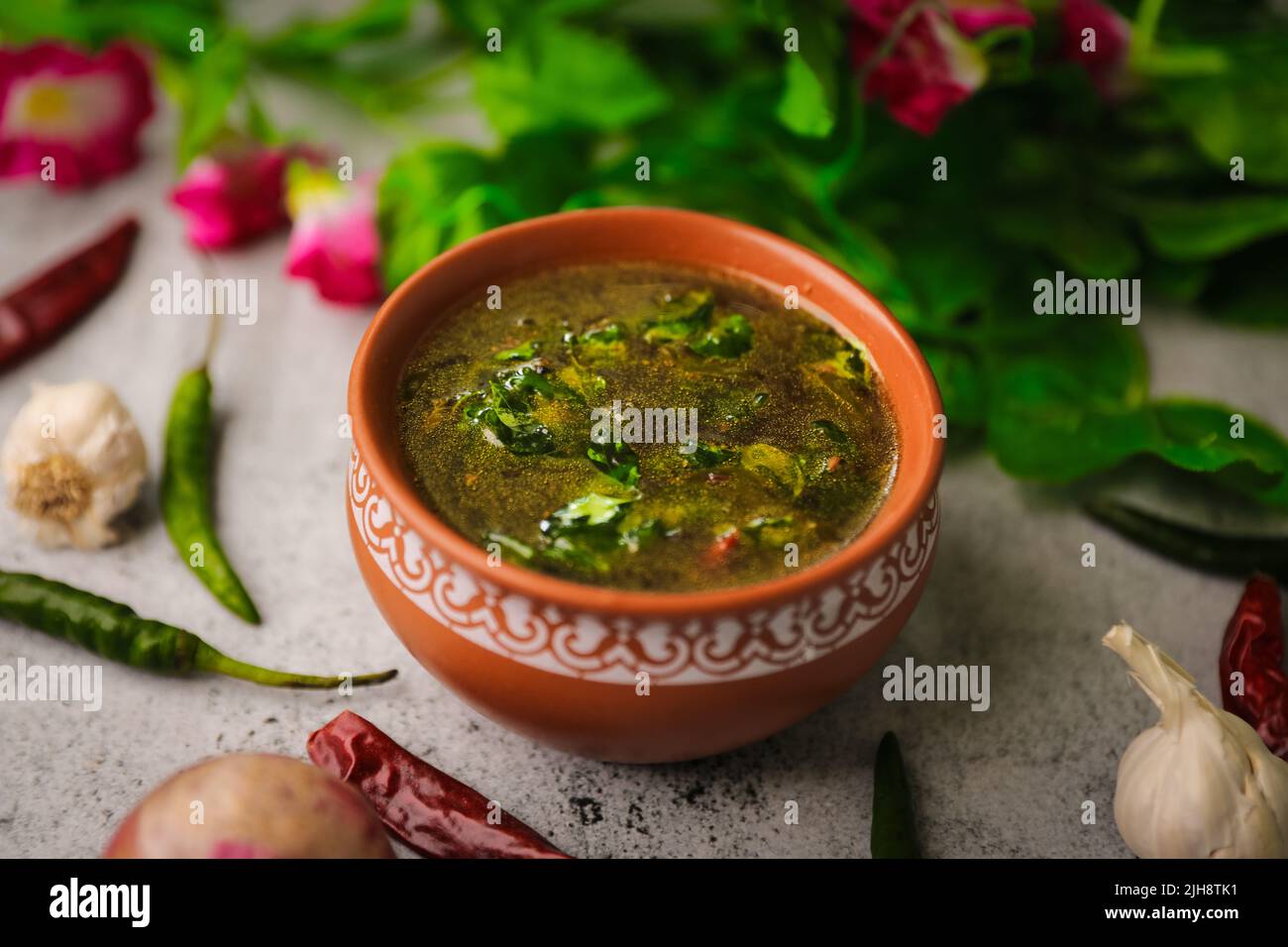 Eine Nahaufnahme einer Schüssel mit fettiger grüner Gourmet-Suppe auf einem Küchentisch mit Zutaten Stockfoto