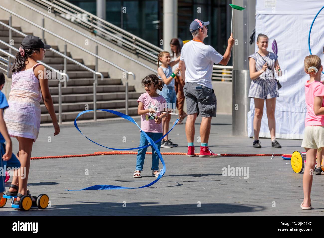Wembley Park, London, Großbritannien. 16.. Juli 2022. Familien lernen beim Zirkus-Skills-Workshop, wenn der International Busking Day wieder im Wembley Park ist. Das kostenlose, ganztägige Festival hat große Namen, die sich auf 9 Bühnen mit aufstrebenden Künstlern und Basiskünstlern teilen. Die Veranstaltung im Wembley Park umfasst auch Bereiche für Familienspaß mit Zirkusworkshops, Magie- und Comedy-Acts, Eskapologenroutine, Gesichtsbemalung und Ballonkünstler. Der internationale Bucking Day, der vom Bürgermeister von London unterstützt wird, wird von Busk in London präsentiert. Amanda Rose/Alamy Live News Stockfoto