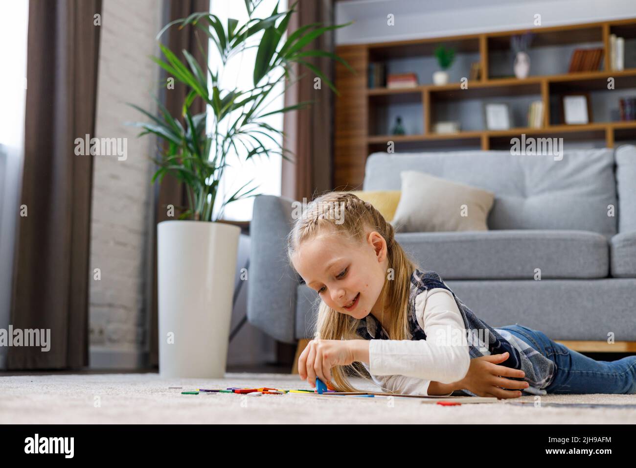 Pädagogisches Spielzeug für Kinder. Niedliches kleines Mädchen, das zu Hause ein Holzpuzzle mit bunten Blöcken auf dem Teppich macht. Gehirn Teaser Spielzeug für Motor Stockfoto
