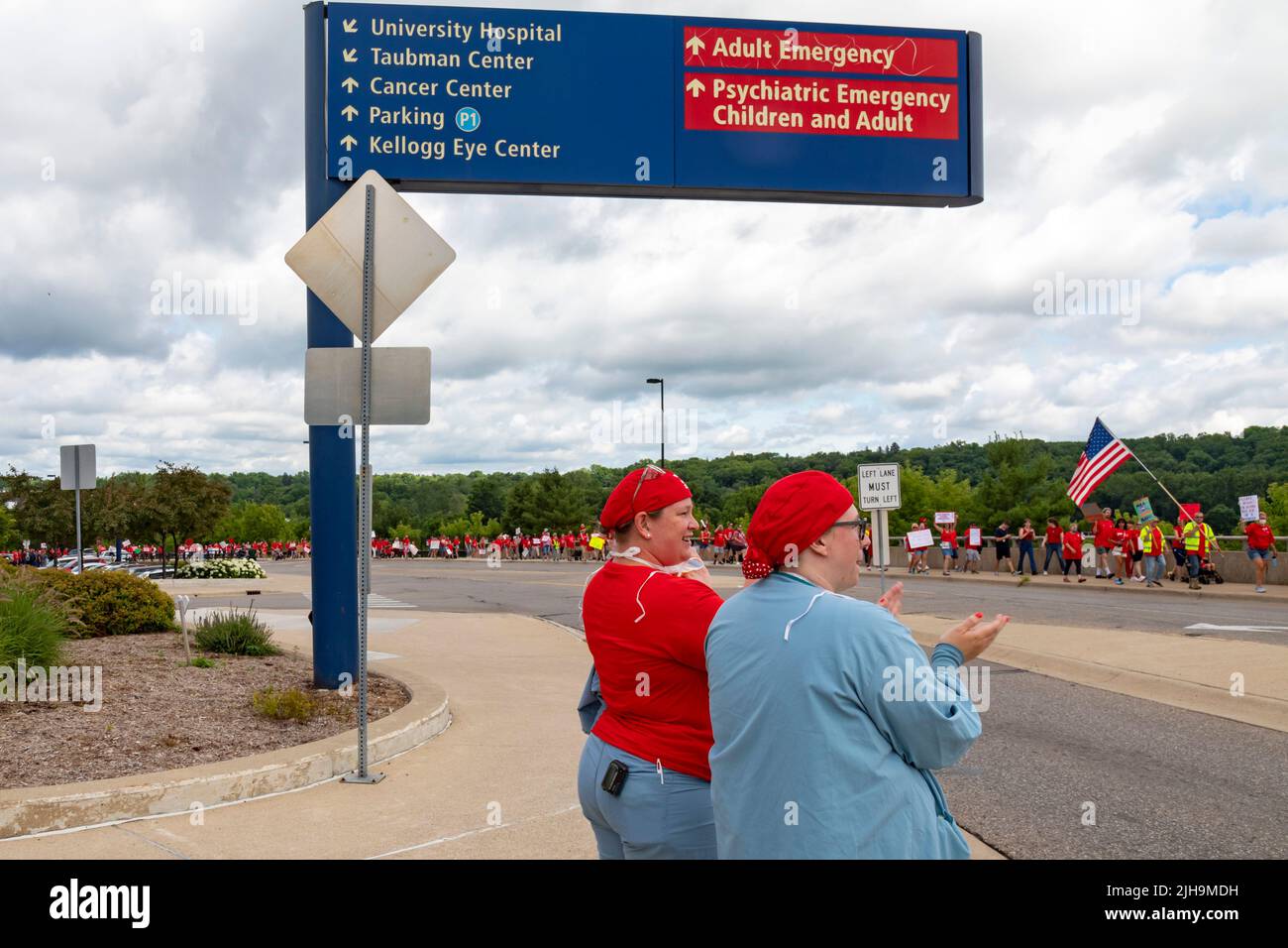 Ann Arbor, Michigan, USA. 16.. Juli 2022. Mehr als tausend Krankenschwestern und Unterstützer der Gemeinde protestierten gegen das Krankenhaus der University of Michigan und protestierten gegen die zögerliche Führung bei den Verhandlungen über Gewerkschaftsverträge. Die Michigan Nurses Association will obligatorische Überstunden beseitigen und die Arbeitsbedingungen verbessern, die Krankenschwestern sagen, dass sie die Patientenversorgung negativ beeinflussen. Zwei Krankenschwestern mit Peelings kamen heraus, um den Spitzern zu applaudieren. Kredit: Jim West/Alamy Live Nachrichten Stockfoto