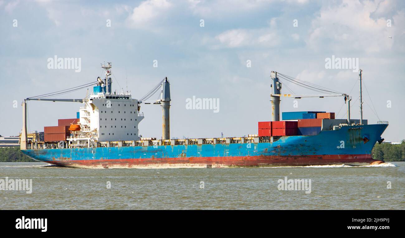 Das Schiff Typ Containerschiff, das mit Containern beladen ist, fährt neben dem Ufer Stockfoto